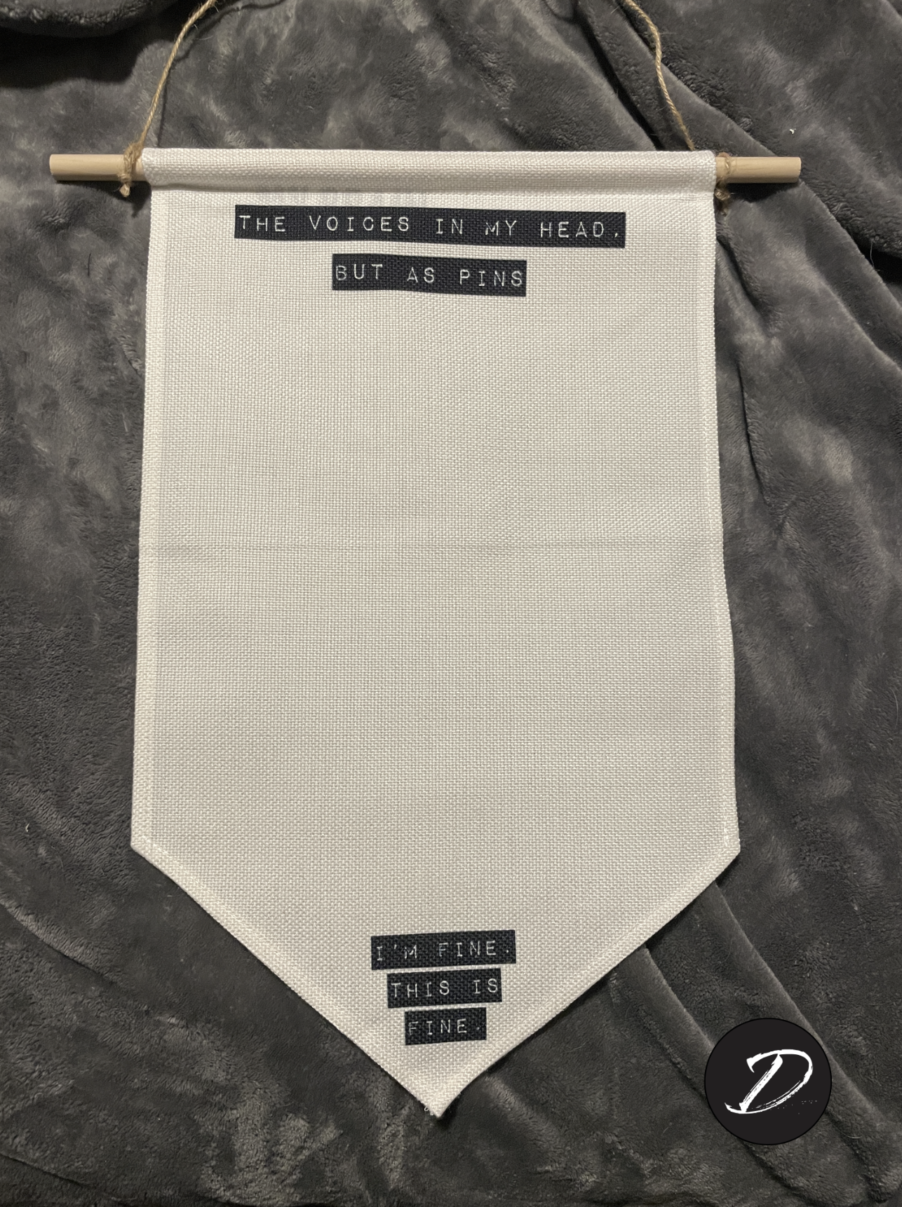 Hanging wall banner for pins with retro label-maker style text blocks. Top text reads "The Voices In My Head, But As Pins." Bottom text reads "I'm Fine. This Is Fine."